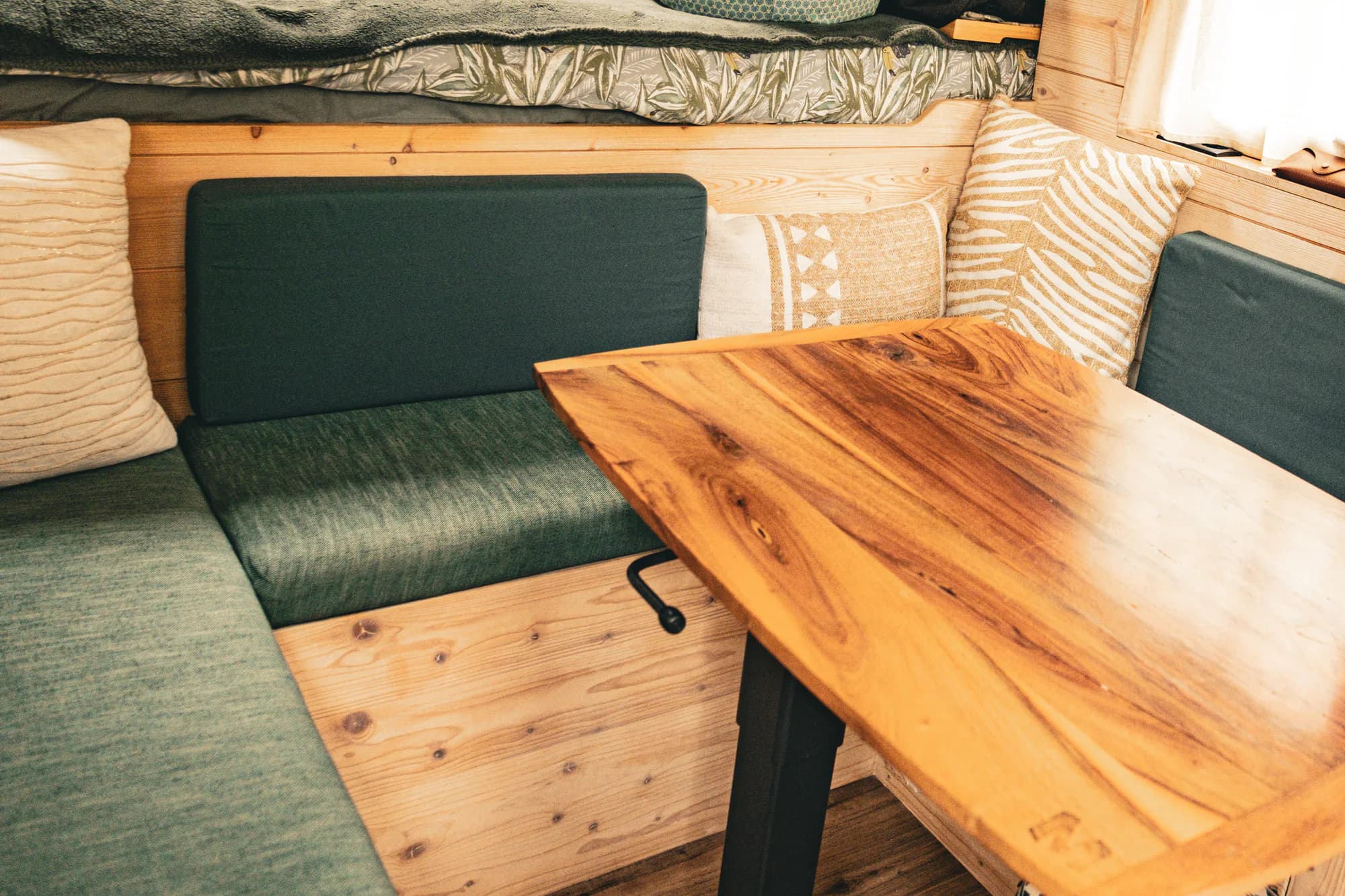 Banquette verte sur mesure installée dans un fourgon aménagé.