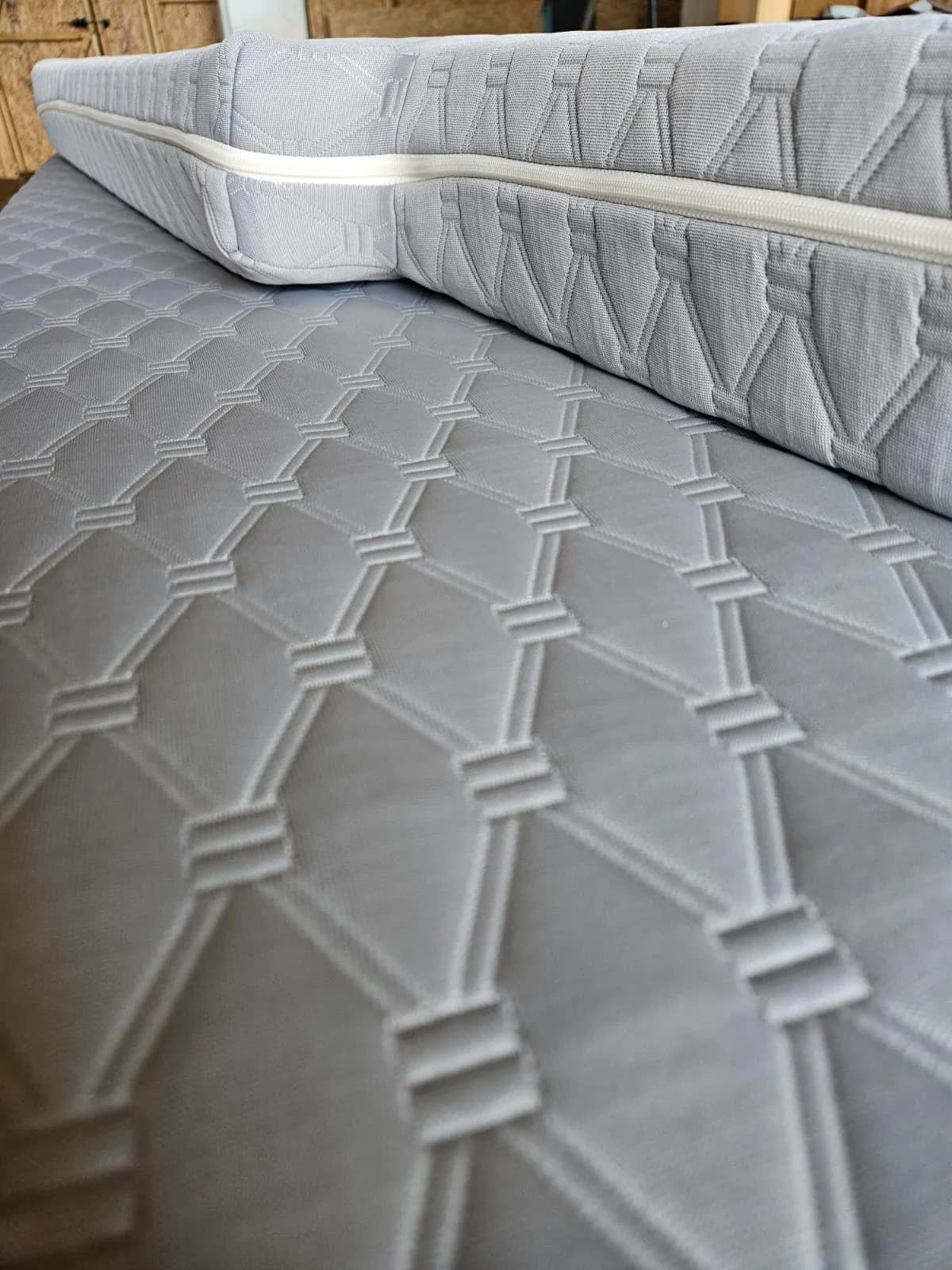 Gros plan sur la housse grise d’un matelas nomade.