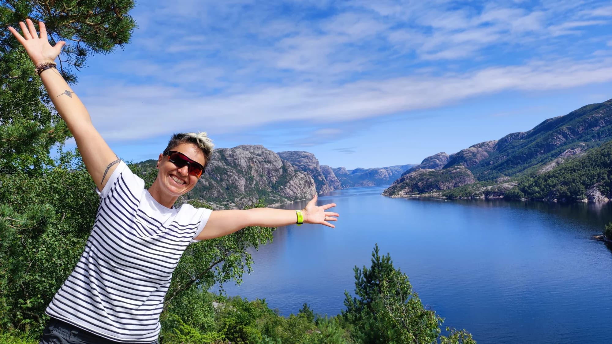 Barbara ouvre les bras devant un fjord entouré de montagnes.