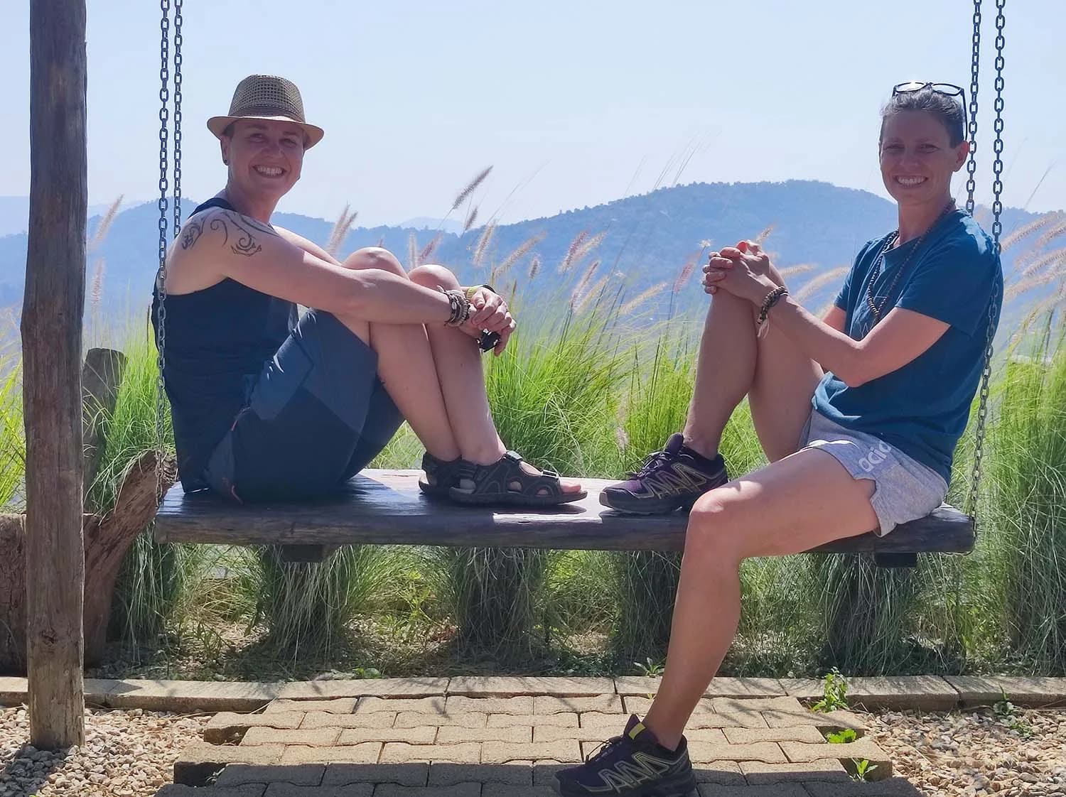 Barbara et Valérie assises sur une grande balançoire en pleine nature.