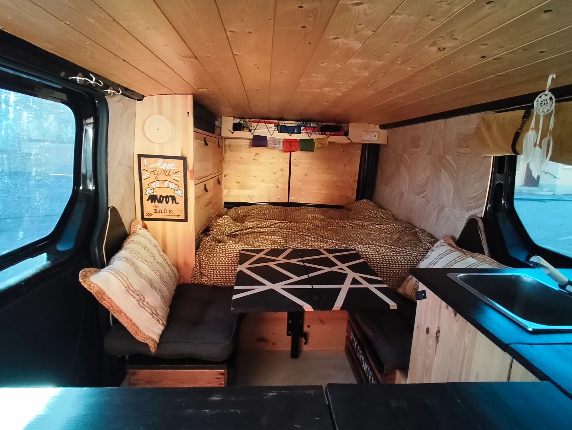 L’intérieur en bois de Ch’tiot Bidule avec lit, table et coin cuisine.
