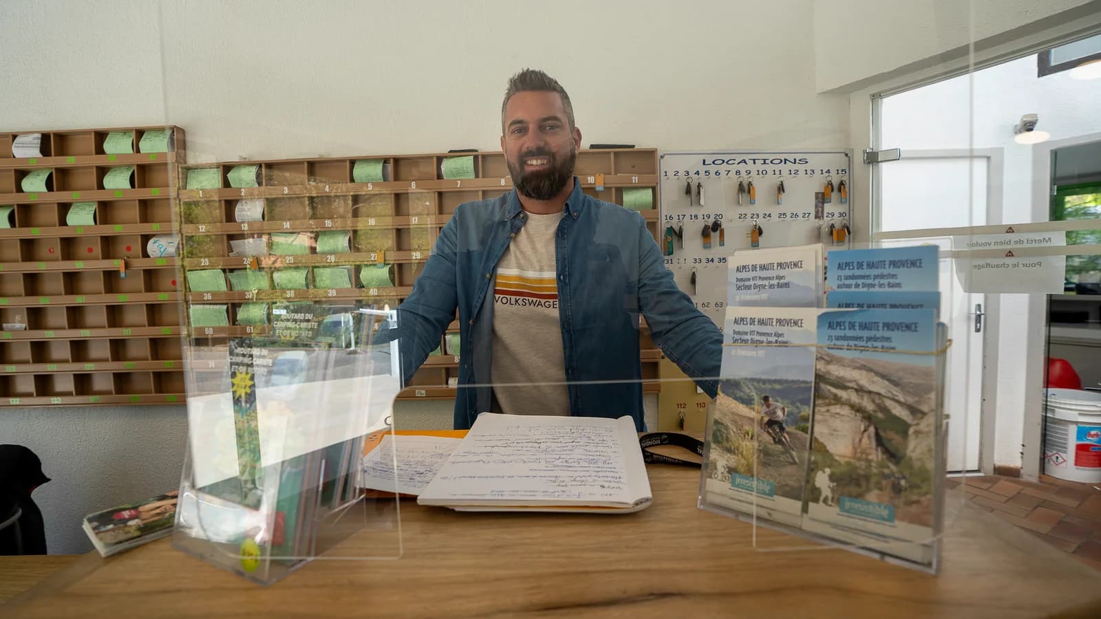 Clément derrière le comptoir de la réception du camping Les Eaux Chaudes